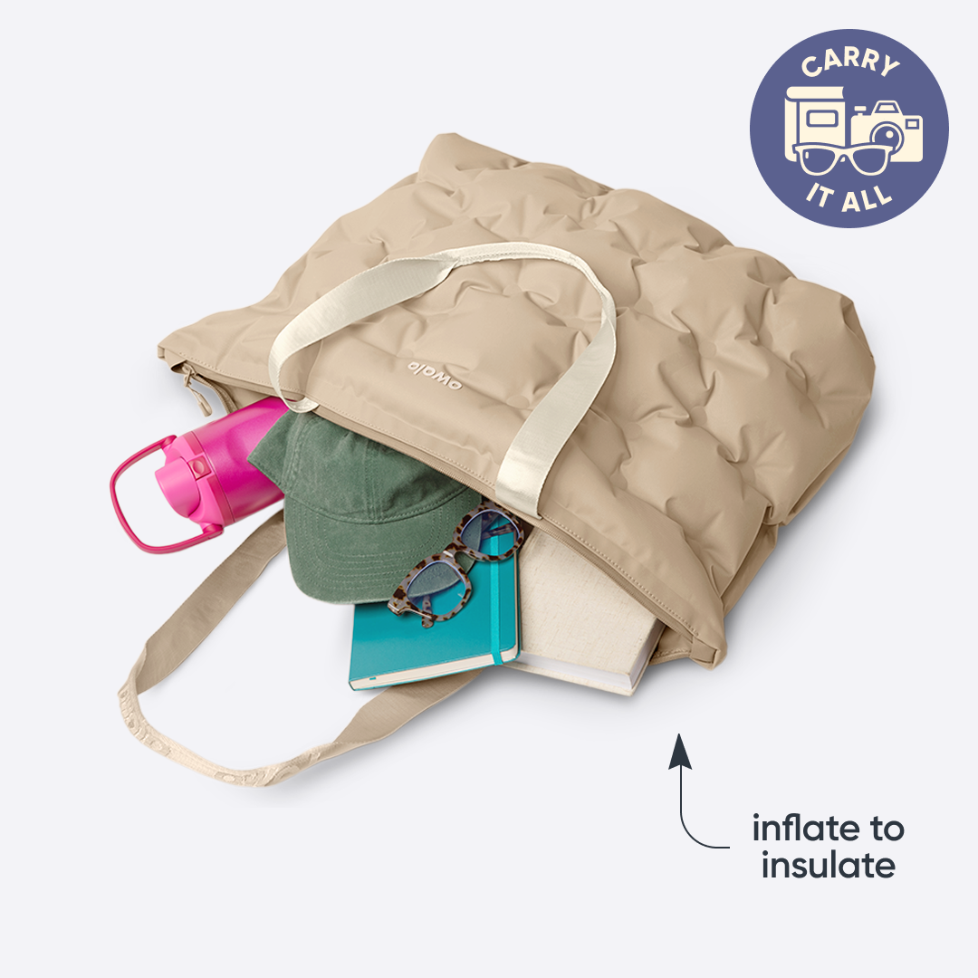 Owala Cloud tote in Al Fresco, cobalt blue inflated tote carrying a yoga mat, notebook, water bottle, and small pouch, with badge reading "CARRY IT ALL" and text overlay reading "inflate to insulate"